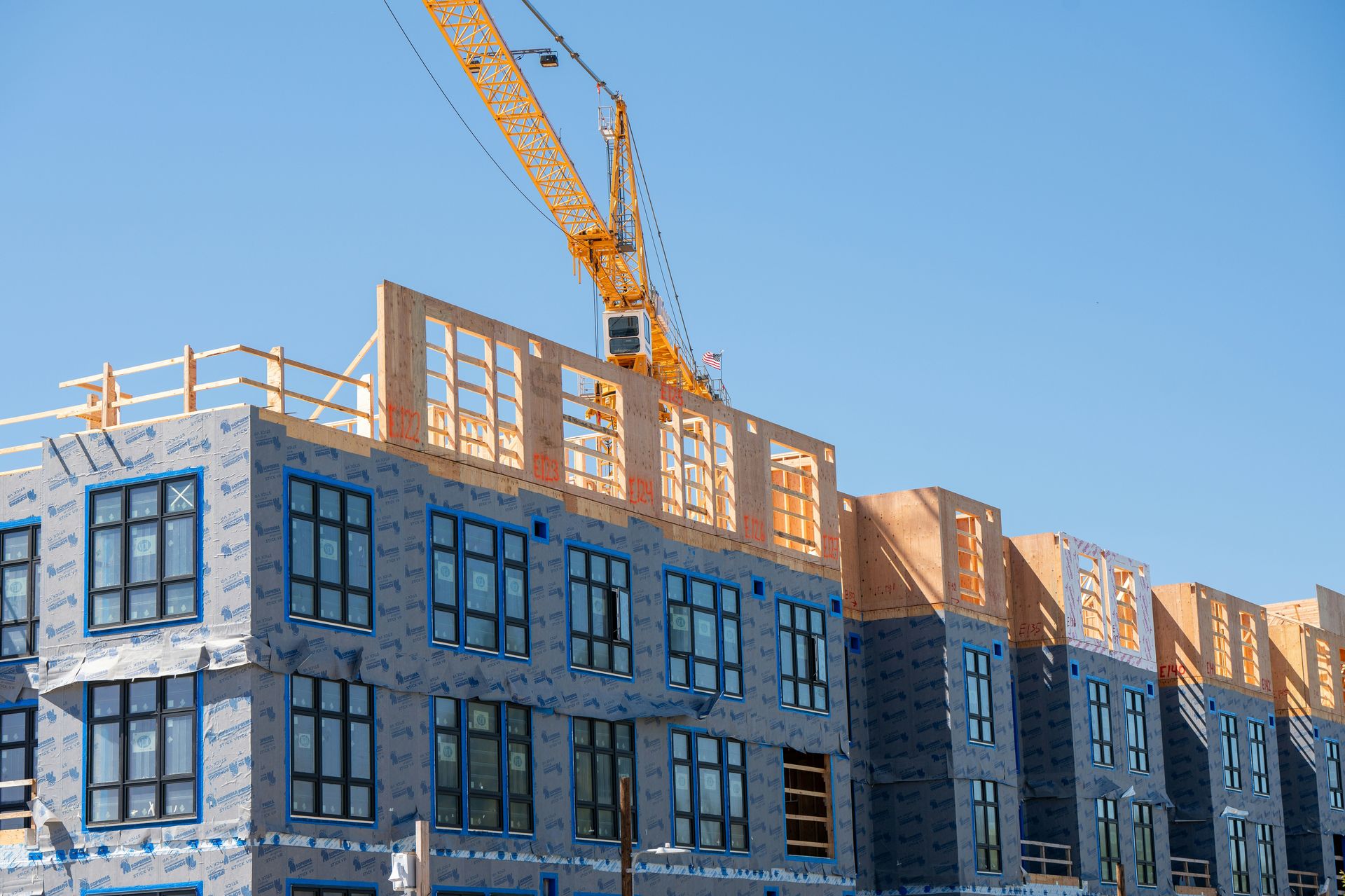 Mid-rise commercial building under construction with a tower crane and wood framing